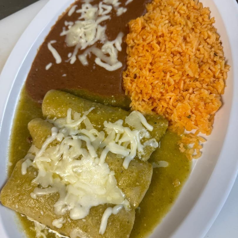 A plate of green enchiladas with melted cheese, refried beans, and orange rice.