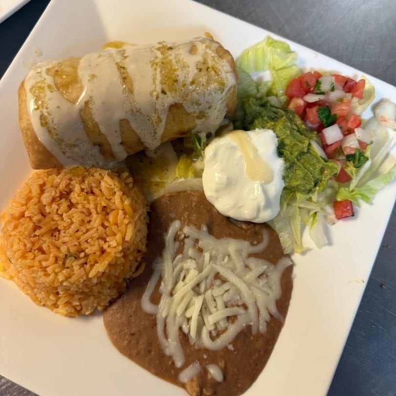A chimichanga with rice, refried beans, guacamole, sour cream, and pico de gallo.